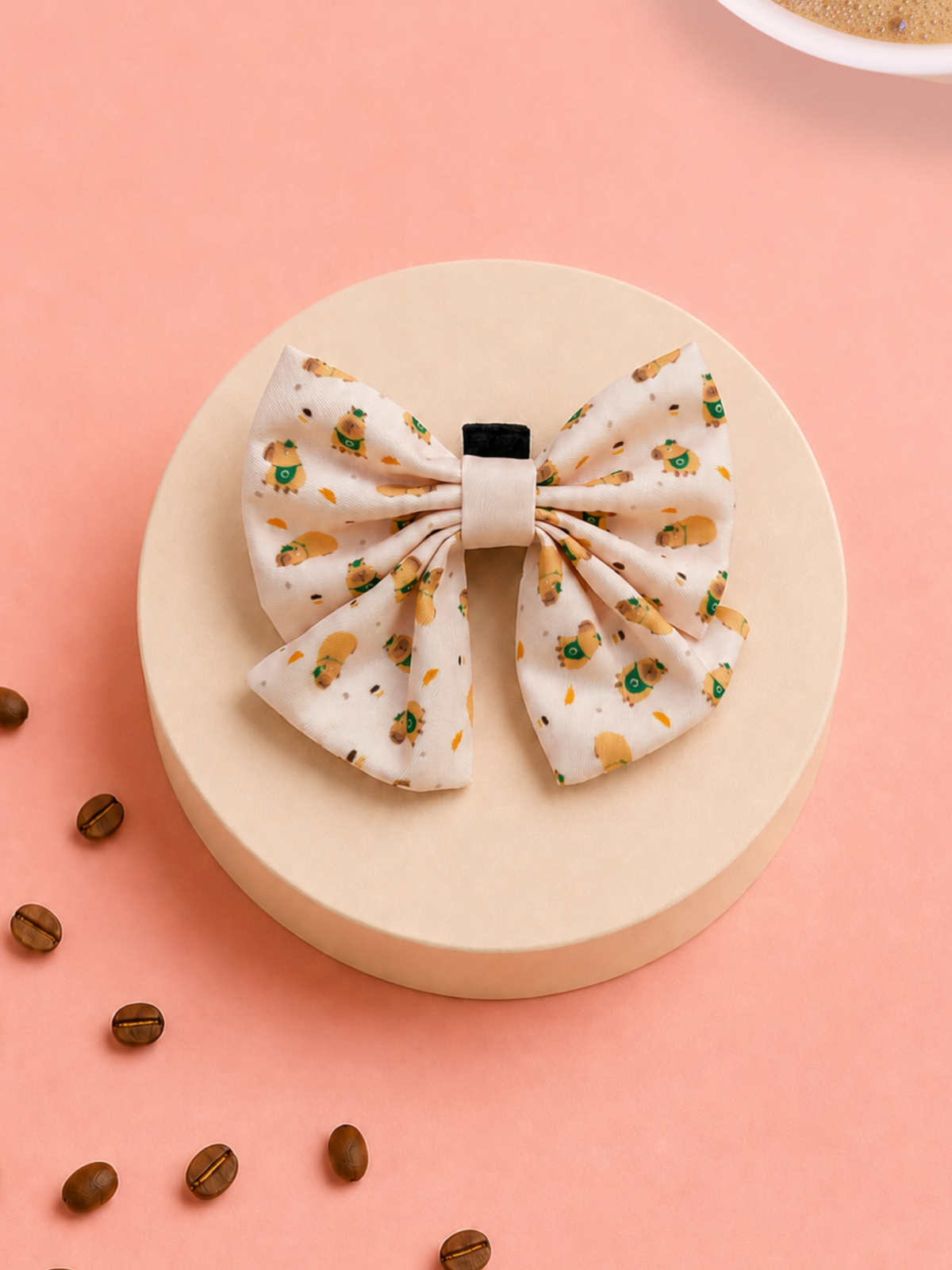 A pup bow with a white base and a small coffee-themed print, displayed on a round beige pedestal with scattered coffee beans on a pink background.